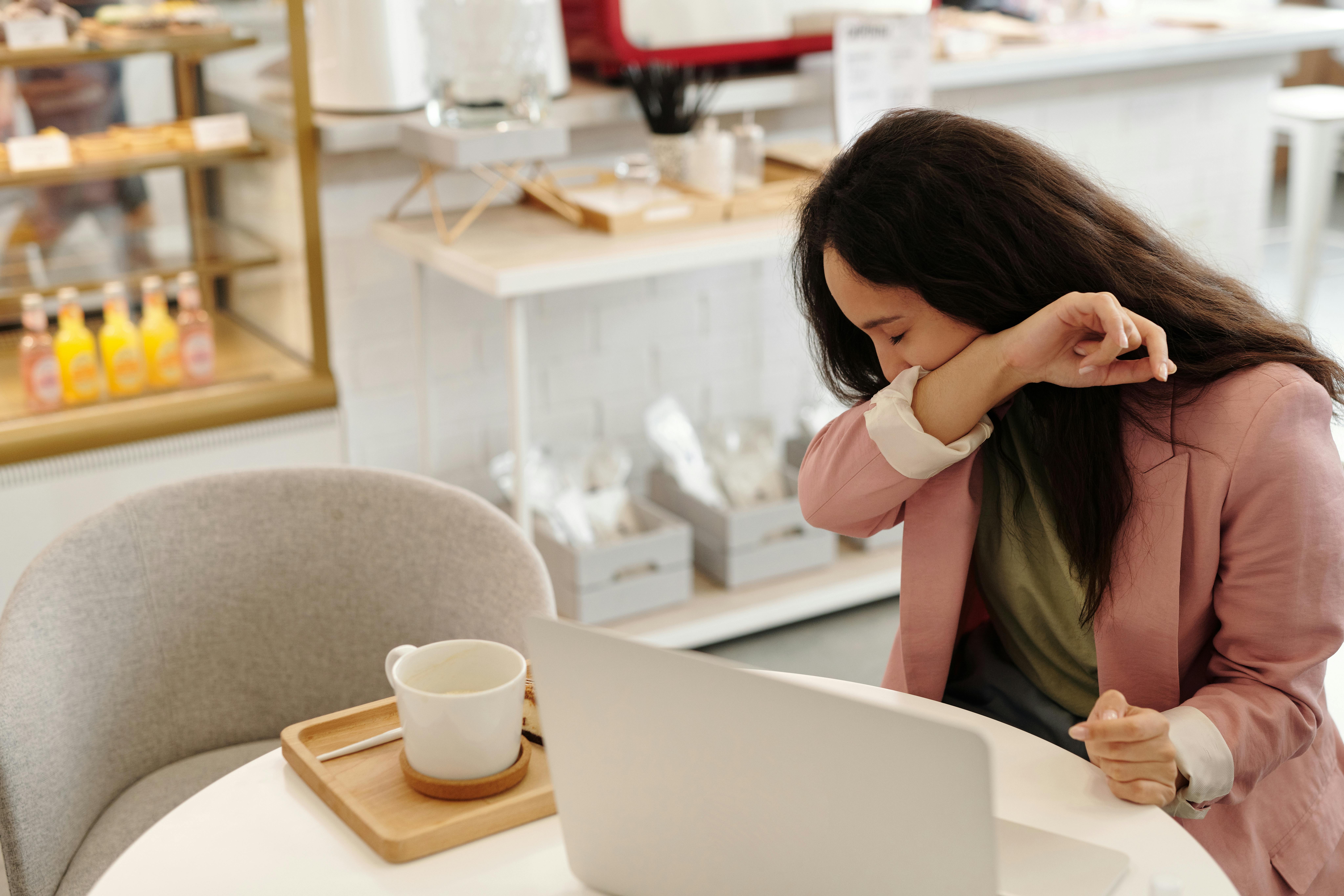 Woman covering a sneeze in a modern cafe, capturing everyday health concerns.