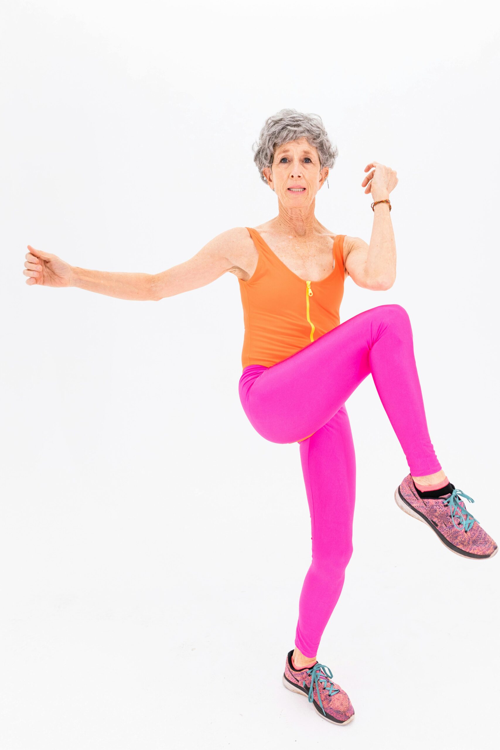 Senior woman in colorful activewear performing fitness routine with energy and grace.